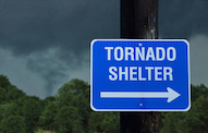Tornado Shelter directional street sign with backdrop of dark and cloudy skies